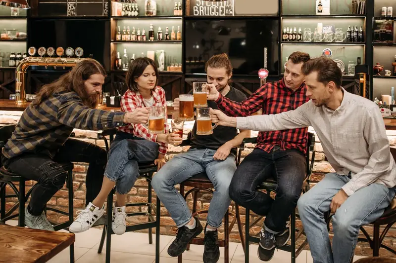 Freundesgruppe stößt in einer Kneipe mit Bier an