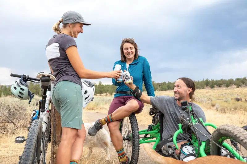 Freunde machen mit dem Rad Pause und stoßen mit Bier an