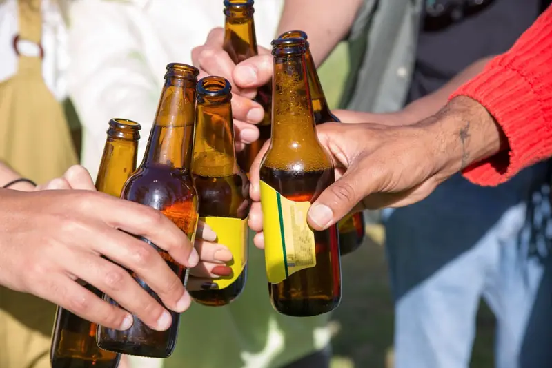 Hände stoßen mit Bierflaschen an
