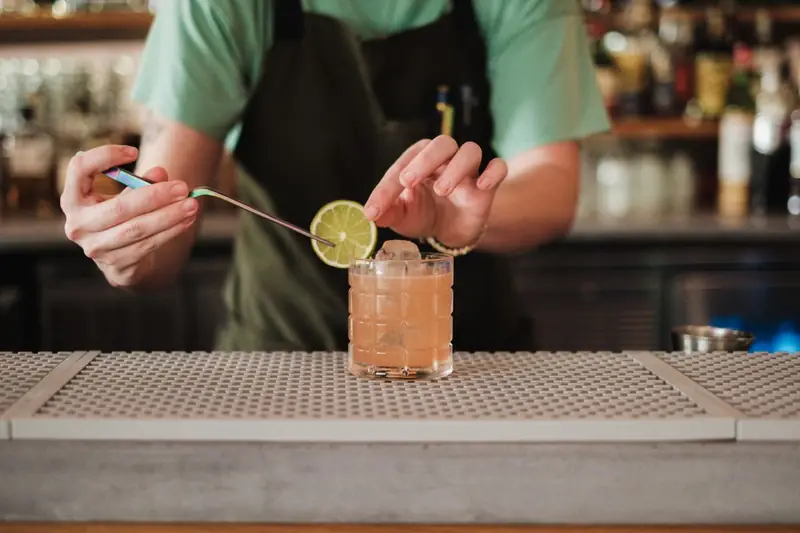 Cocktail wird mit einer Limettenscheibe garniert