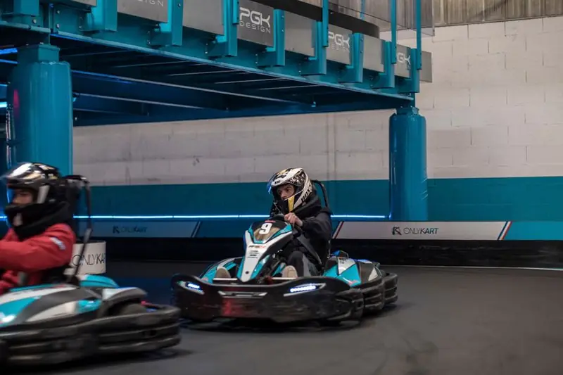 Zwei Fahrer im Kart auf einer Indoor-Strecke