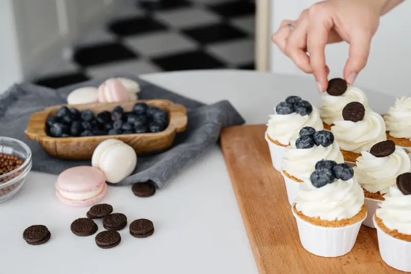 Cupcakes werden mit Creme, Beeren und Keksen verziert
