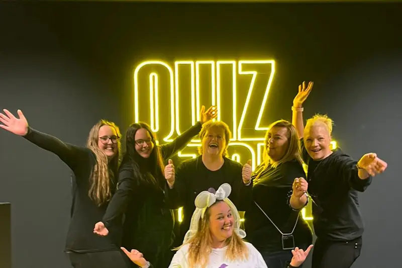JGA-Gruppe jubelt vor dem Leuchtschriftzug der QUIZ ZONE