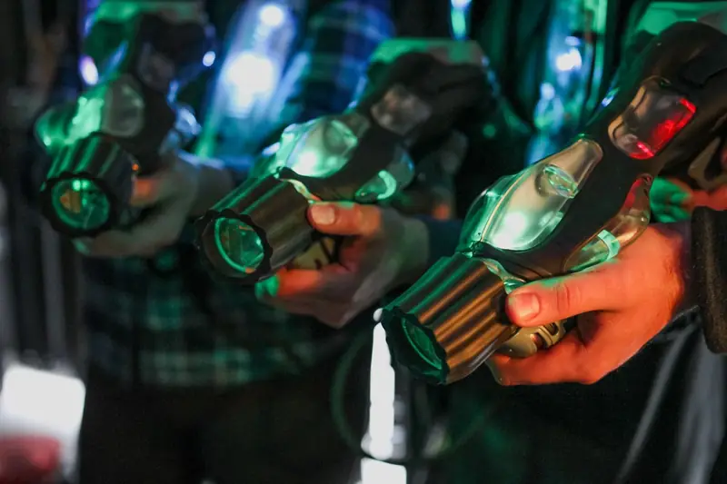 Spieler halten leuchtende Lasertag-Phaser