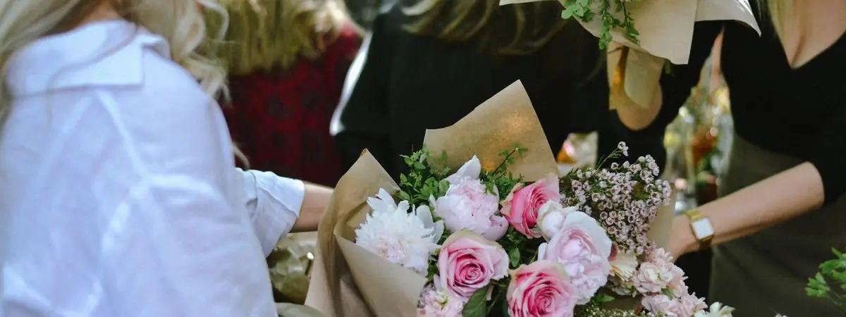 Frauen binden gemeinsam Sträuße mit rosa Rosen