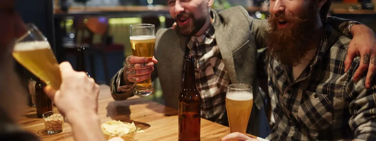 Drei Freunde mit Bier und Snacks am Kneipentisch